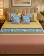 Blue floral and bird-print bed ensemble with yellow and dusty pink panels and matching cushion covers