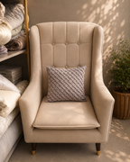 Taupe cushion cover with a woven basket pattern displayed on a cream chair