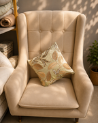 Sage green cushion cover with gold and beige embroidered leaves on a cream chair