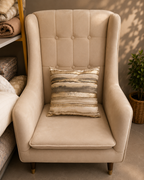 Beige and grey cushion cover with abstract gold stripes on a cream chair