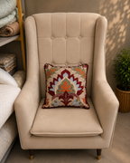 Beige floral cushion cover with burgundy, rust and green design on a cream chair