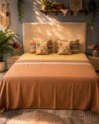 Terracotta and mustard bed ensemble with striped pillow covers and floral decorative cushions